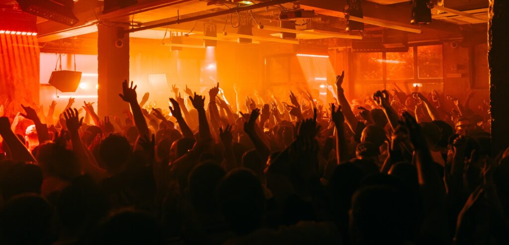 Crowd with hands up under orange lights